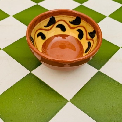 Taça de cerâmica amarelo e castanho sobre mesa quadriculada verde e branca