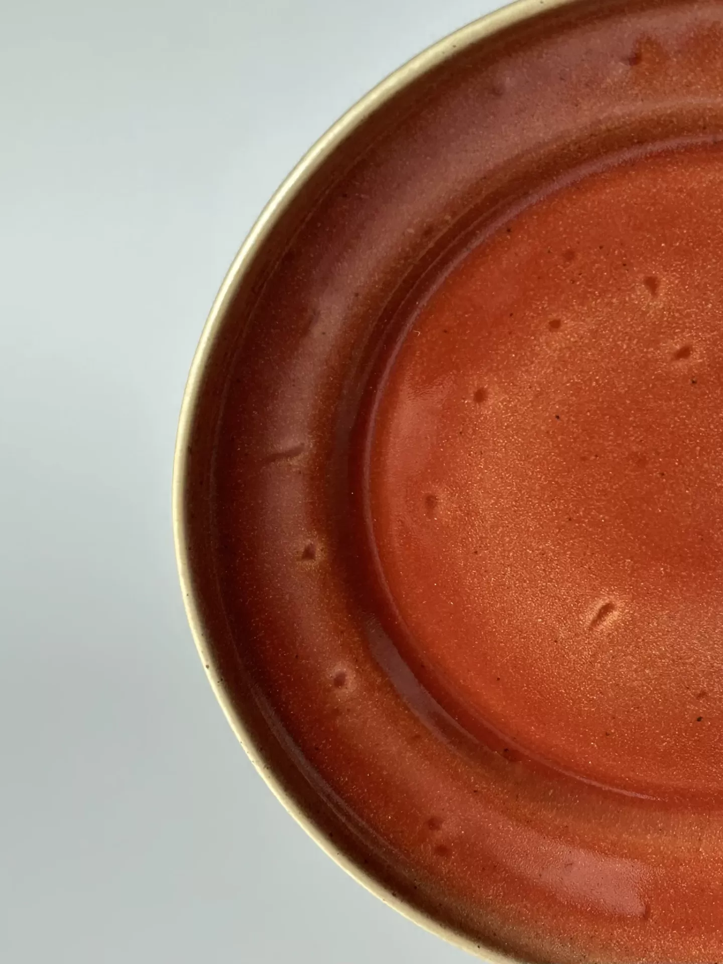 Prato cerâmico castanho avermelhado com borda clara e textura irregular