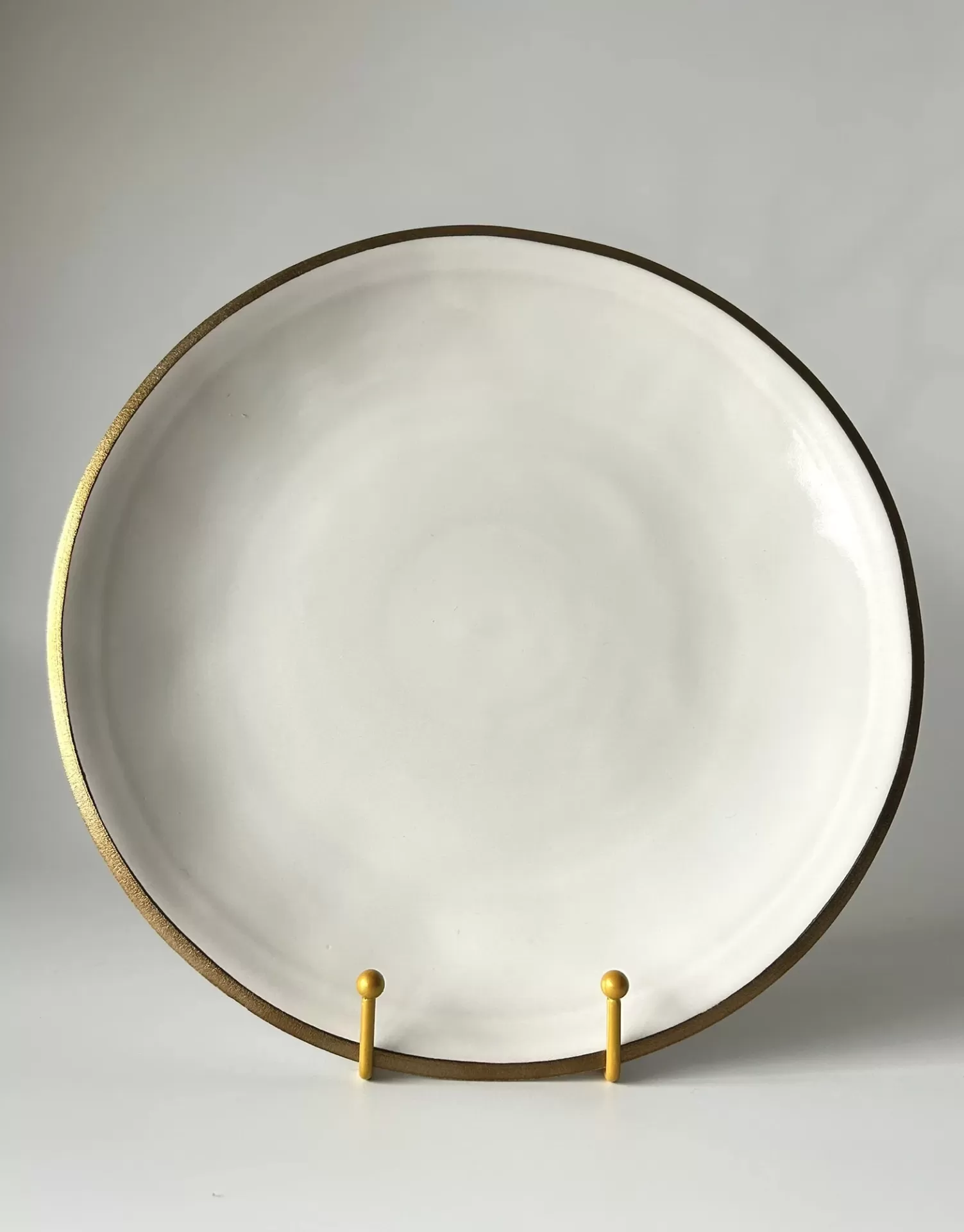 Prato redondo branco com borda dourada num suporte