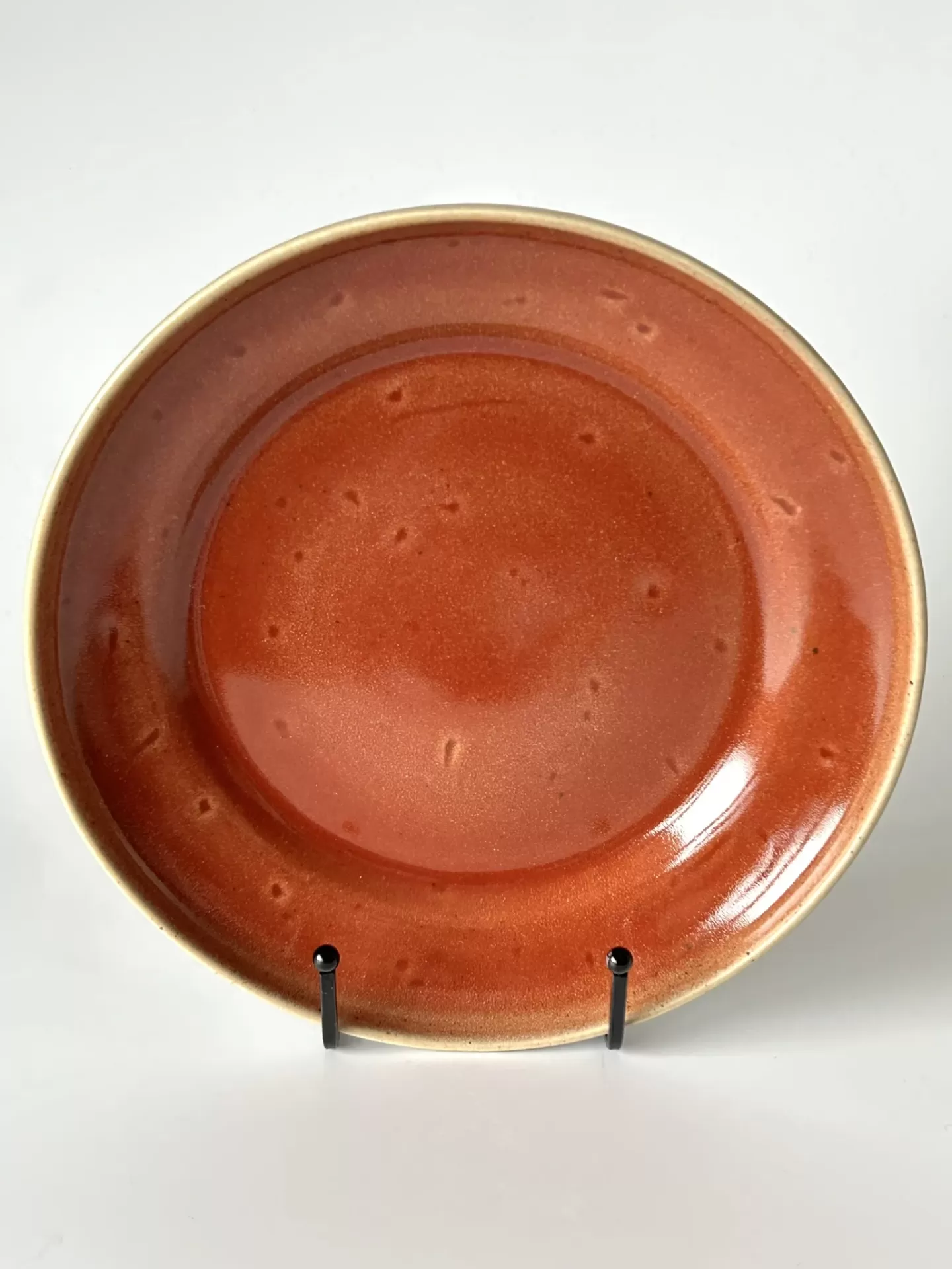 Prato cerâmico laranja com textura pontilhada em suporte preto