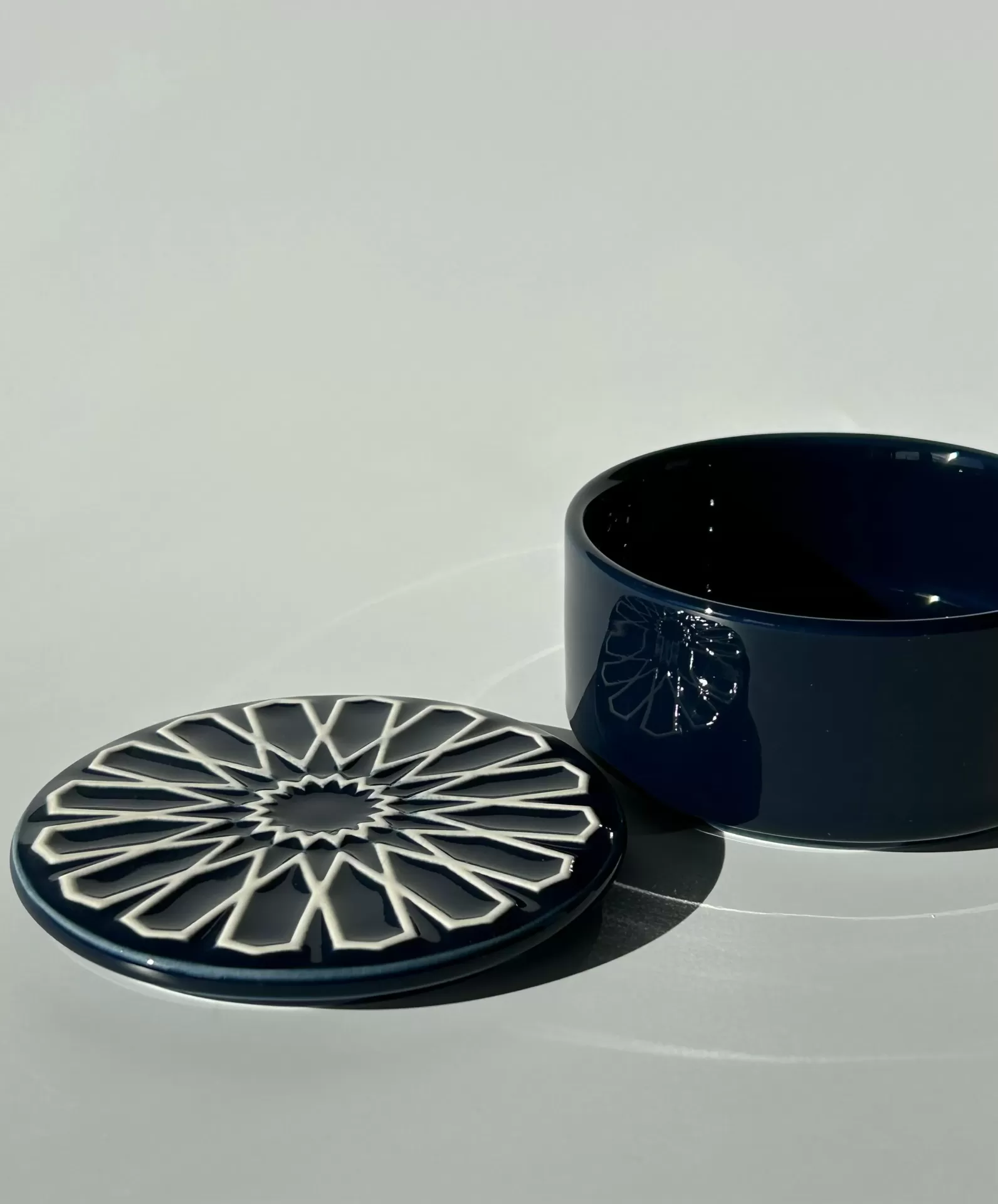 Caixa redonda azul escuro em cerâmica com tampa decorada em padrão geométrico