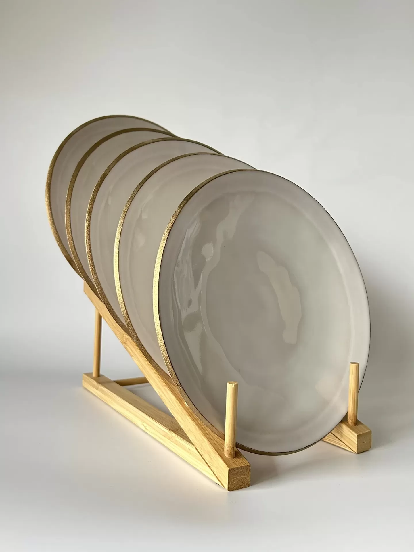 Cinco pratos cinzentos com borda dourada num suporte de madeira