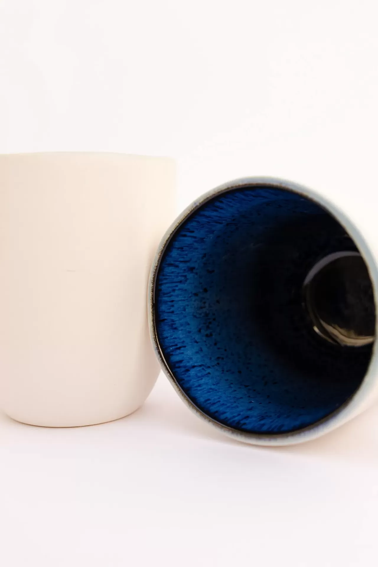 Dois copos cerâmicos, um branco e outro com interior azul