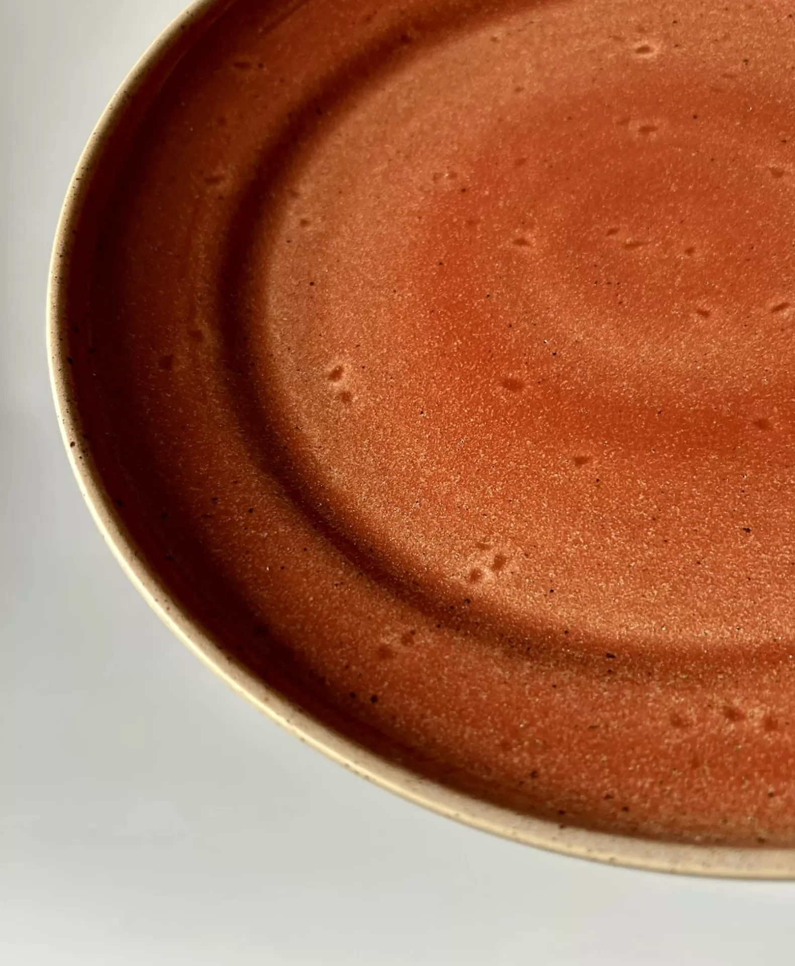 Prato de cerâmica vermelho com borda bege sobre fundo claro