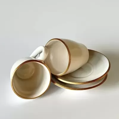 Conjunto de chávenas e pires brancos com bordas douradas em fundo branco.