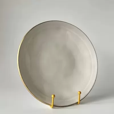 Prato branco com bordo dourado em suporte amarelo