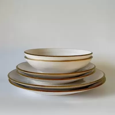 Conjunto de pratos brancos com bordas douradas empilhados