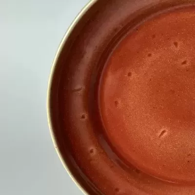 Prato cerâmico castanho avermelhado com borda clara e textura irregular