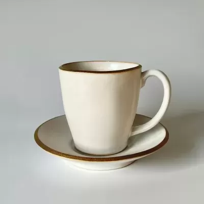 chávena creme com bordas douradas sobre pires