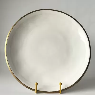 Prato redondo branco com borda dourada num suporte