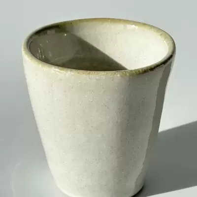 Copo de cerâmica bege claro com acabamento vidrado em fundo branco