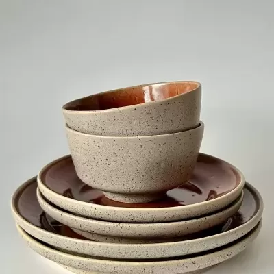 Conjunto de loiça cerâmica com tigelas e pratos em tons bege e castanho avermelhado.