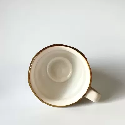 Caneca branca de cerâmica com borda dourada vista de cima