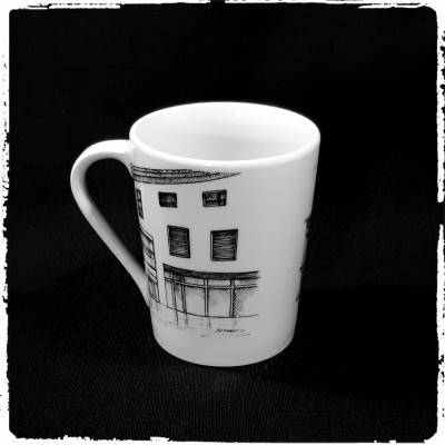 Caneca de cerâmica branca com desenho a preto de fachada de edifício