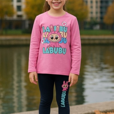 Conjunto infantil rosa e azul com personagem e texto LABUBU, calças azul-escuras e ténis brancos num ambiente exterior junto a lago.