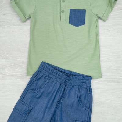Conjunto infantil t-shirt verde clara com bolso azul e calções azuis escuros.