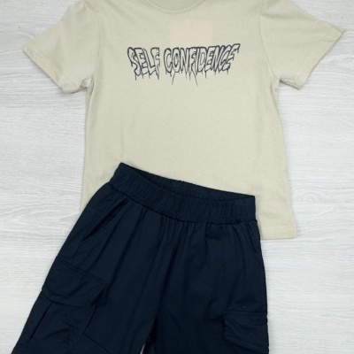 Conjunto infantil t-shirt bege com texto e calções pretos com bolsos.