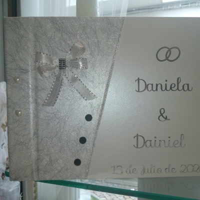 Livro de assinatura para casamento em capa prateada com laço, pérolas e texto. 