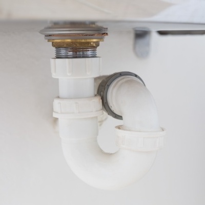 Tubo sifão de plástico branco sob pia