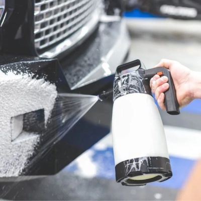 Pulverizador a aplicar espuma em frente de automóvel preto