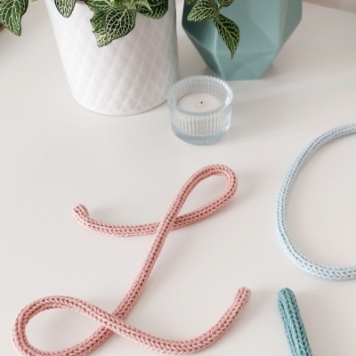 Mesa com planta em vaso branco, vaso azul geométrico, castiçal de vidro e cordões trançados coloridos.