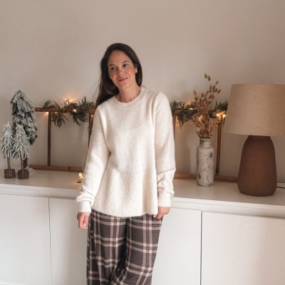 Mulher com camisola branca e calças aos quadrados em ambiente interior com decoração