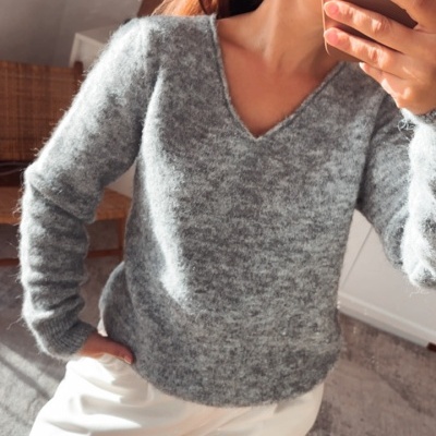 Suéter cinzento de malha felpuda e calças brancas em ambiente interior