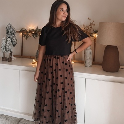 Vestido preto e castanho com corações pretos usado por mulher em sala decorada