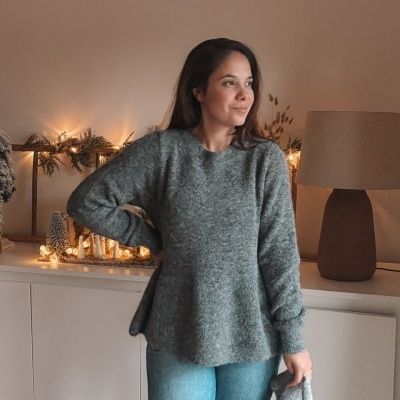 Mulher com camisola cinza e calças de ganga em sala com decoração de Natal