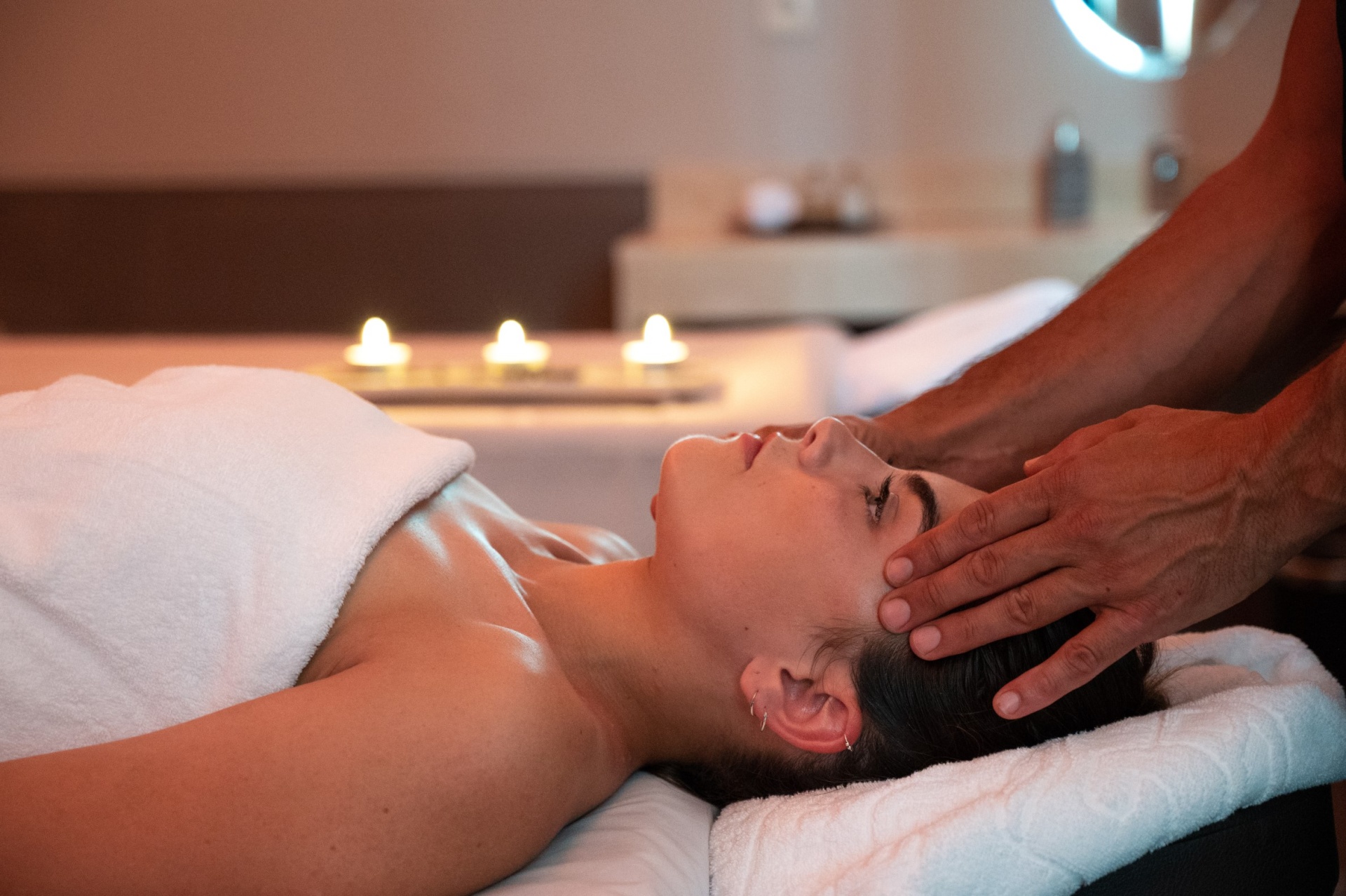 Viagem à medida Pessoa a receber massagem na cabeça em ambiente de spa com velas