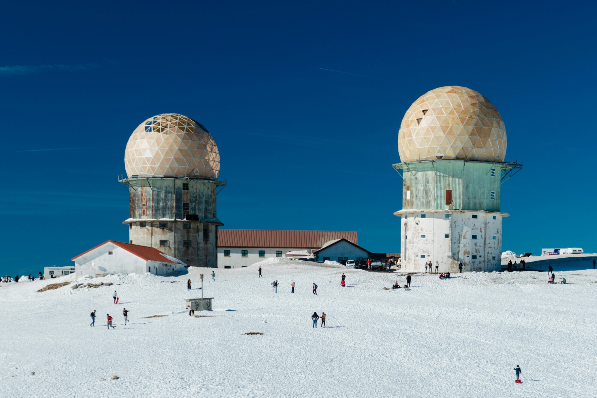 Serra da Estrela – Férias de Natureza e Tradição no Coração de Portugal Duas estruturas esféricas tipo radar com padrões geométricos em terreno nevado e céu azul