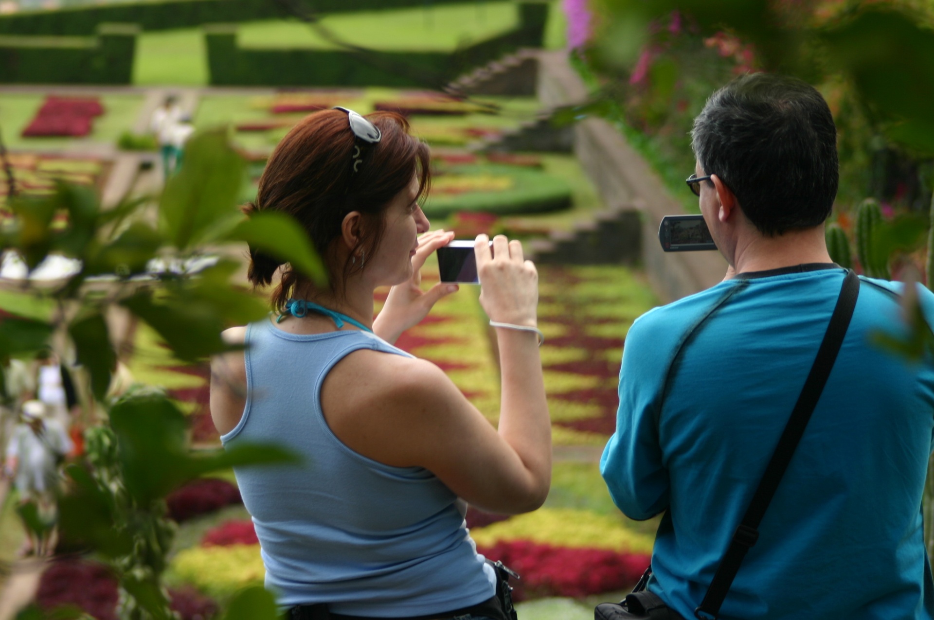 Viagem à medida Duas pessoas a tirar fotos num jardim colorido de flores, vista de costas.