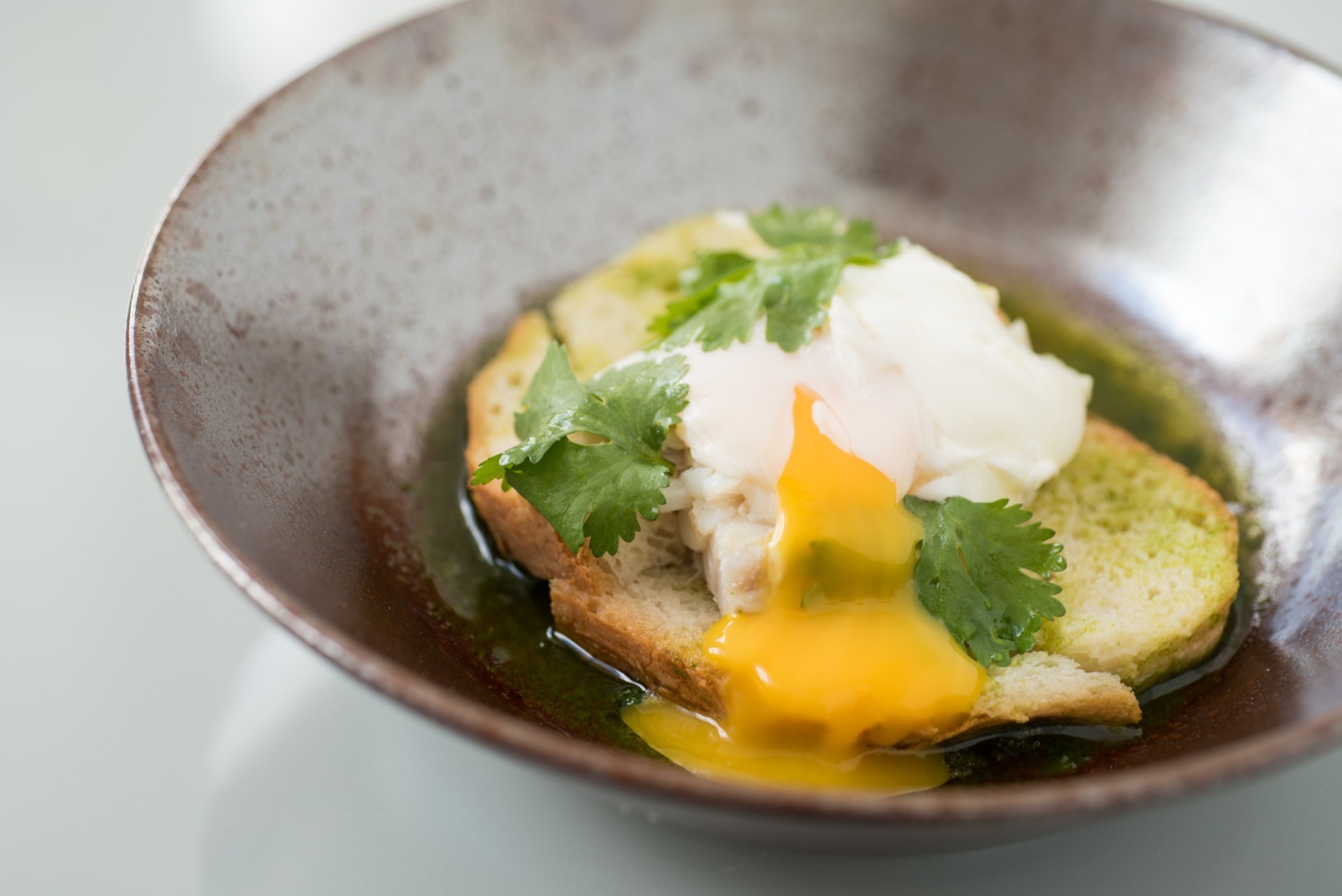 Viagem à medida Ovo escalfado com pão e coentros numa tigela castanha