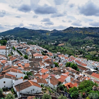 vila com casas brancas e telhados vermelhos com paisagem montanhosa verde