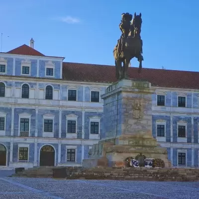 Estátua de cavalo e cavaleiro em praça com edifício azul ao fundo