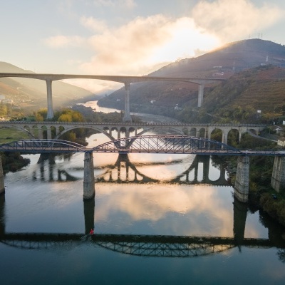 Três pontes sobre um rio entre colinas ao pôr do sol