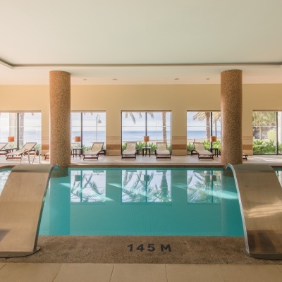 Piscina interior com cascatas metálicas e vista para o mar