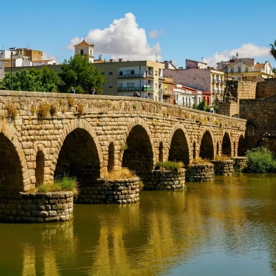 Ponte de pedra com arcos sobre rio e edifícios urbanos ao fundo