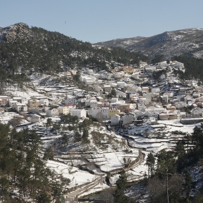Aldeia branca com neve em montanhas e árvores verdes