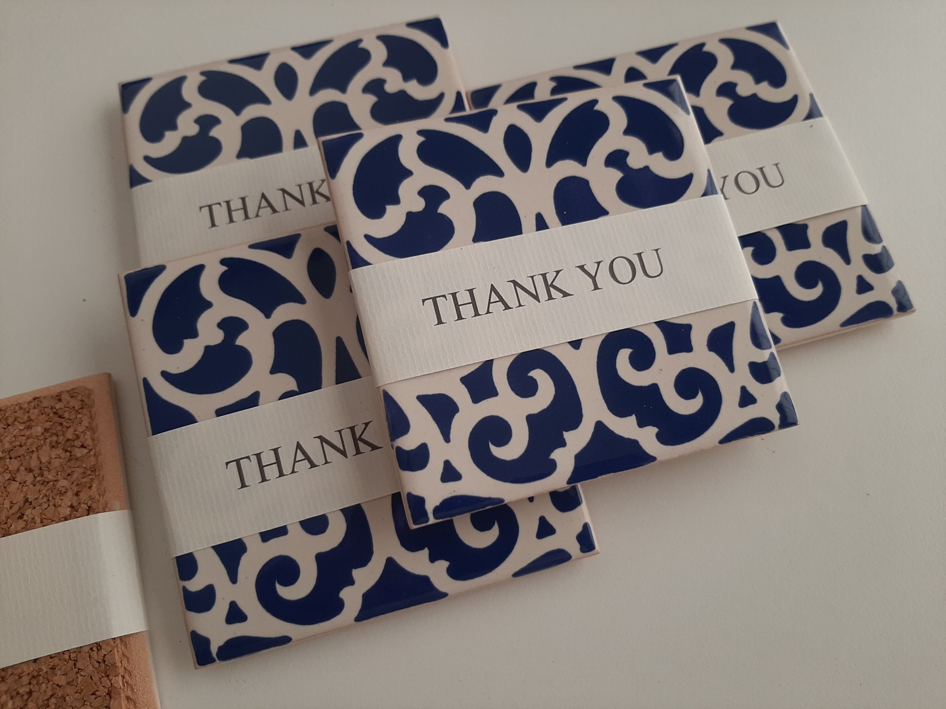 Blue and white patterned coasters with THANK YOU bands on a light surface