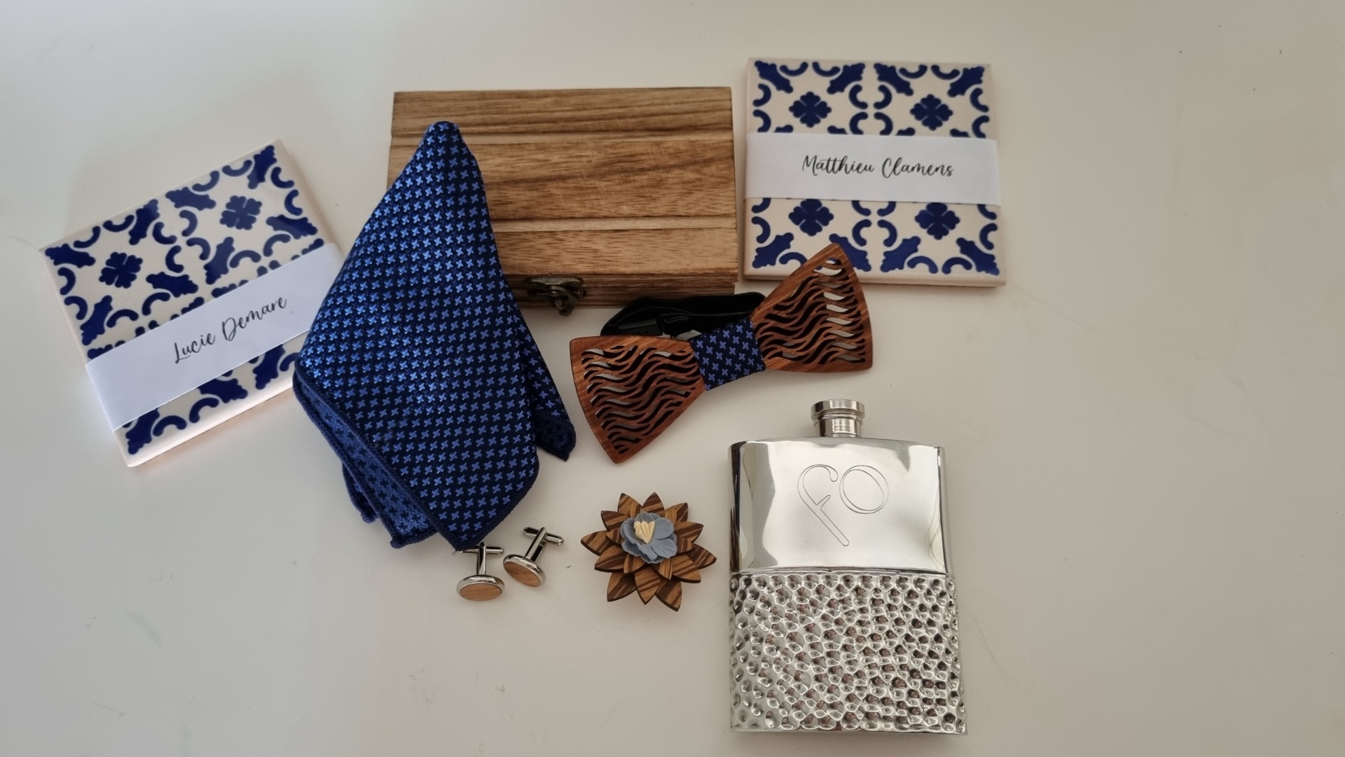 Mens accessories including coasters, pocket square, wooden bow tie, cufflinks, lapel pin, flask, and wooden box on white background