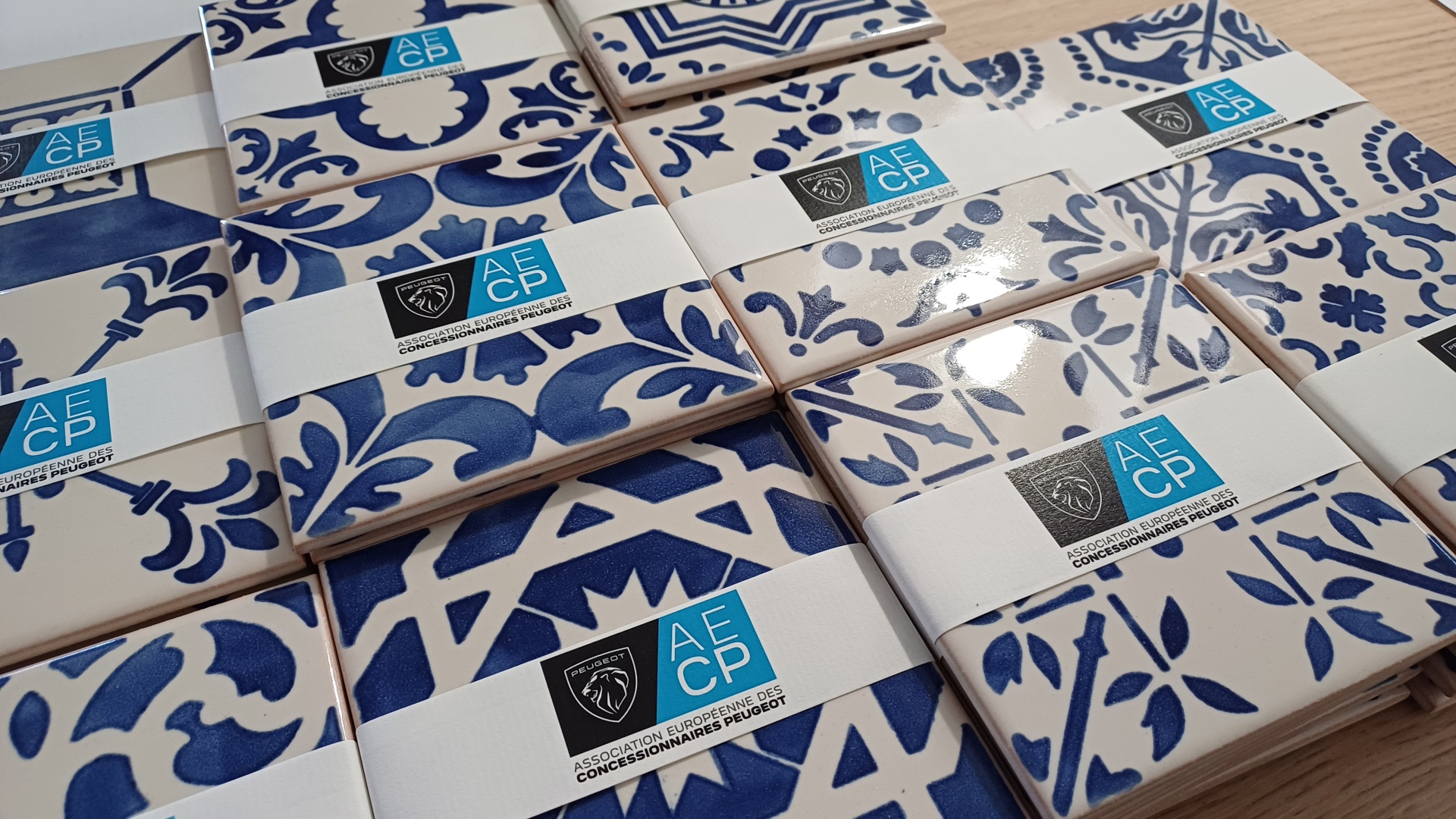 Blue and white patterned ceramic tiles with AECP labels on a wooden surface