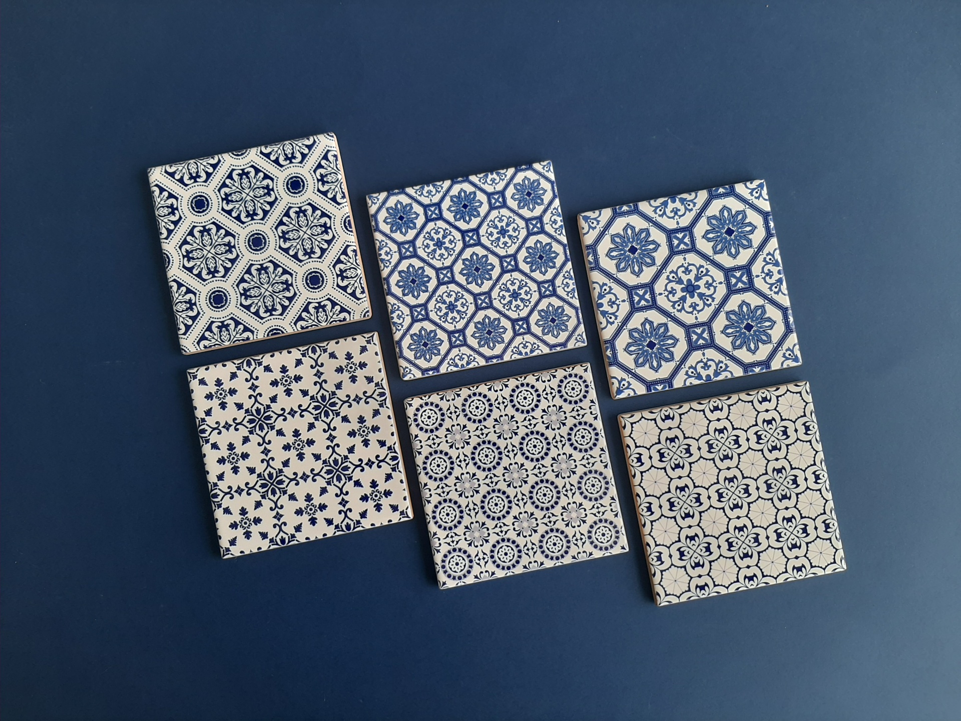 Six blue and white patterned ceramic tiles on blue background