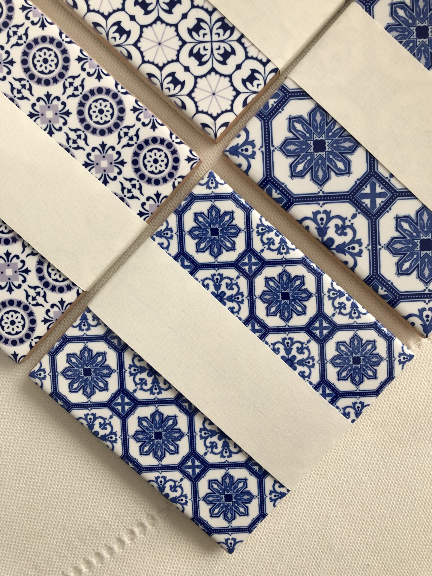 Blue and white patterned ceramic tiles wrapped with beige paper on white fabric