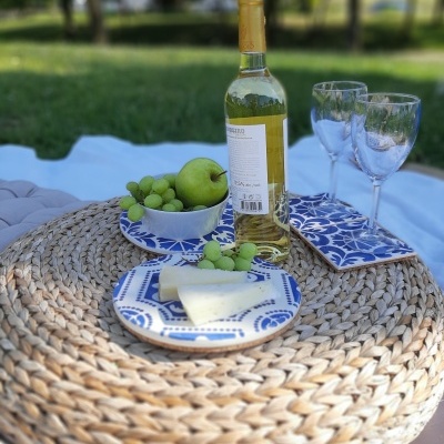 Picnic setup with wine bottle, glasses, fruits, cheese on woven mat