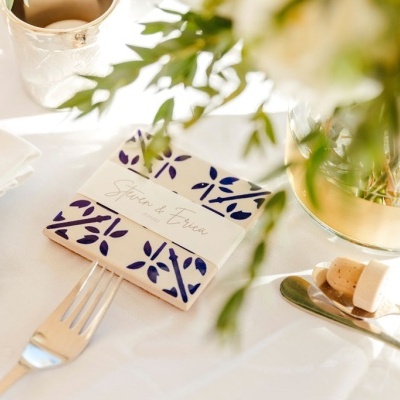 Blue and white patterned ceramic tile with names on a fork at a table setting