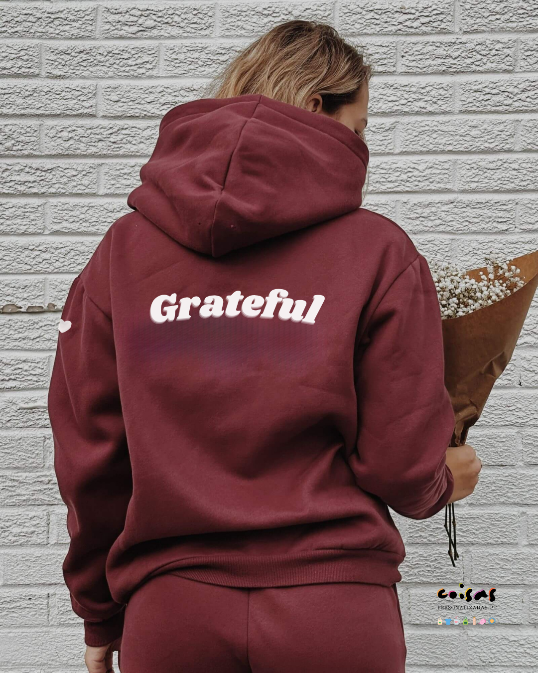 Pessoa de costas a usar hoodie bordô com capuz e texto Grateful em branco nas costas