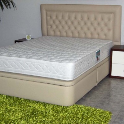 Cama de casal estofada bege com colchão branco e mesa de cabeceira