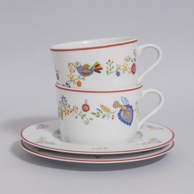 Conjunto de chávenas e pires brancos com padrão floral e decorativo colorido.