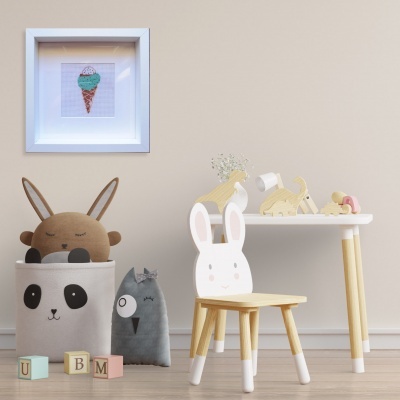 Quarto infantil com mesa branca, cadeira de coelho, caixote de brinquedos panda e quadro de gelado.